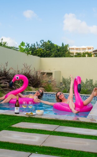 Guests enjoying the private pool with inflatable flamingos at Villa Blenchi Curaçao